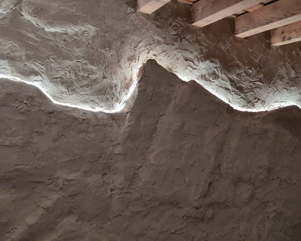 Éclairage LED intégré dessinant une silhouette de montagne sur un mur enduit